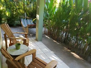 a porch with two chairs and a table and a hammock at Cote Pacific Casitas in Huacas