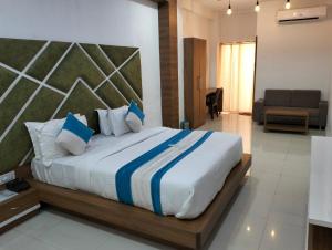 a bedroom with a large bed with blue and white pillows at Hotel Neptune Palace in Anand