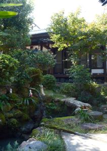 a garden with rocks and trees and a building at ZOKUIJINKAN GUESTHOUSe 続異人館 in Arita