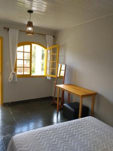 a bedroom with a bed and a table and a window at Casa das Quatro Estações - Lapinha da Serra in Santana do Riacho +1 photo