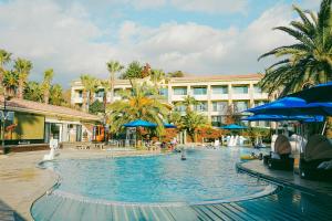 una gran piscina en un complejo con sombrillas azules en Hotel Toscana en Seogwipo