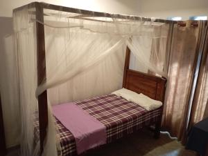 ein kleines Bett mit Baldachin in einem Zimmer in der Unterkunft Surf Forever in Midigama East