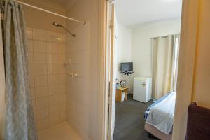 a bathroom with a shower and a bed in a room at Great Western Motel Norseman in Norseman