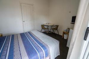 een kleine slaapkamer met een bed en een tafel bij Great Western Motel Norseman in Norseman