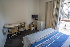 Schlafzimmer mit einem Bett, einem Tisch und einem Fenster in der Unterkunft Great Western Motel Norseman in Norseman