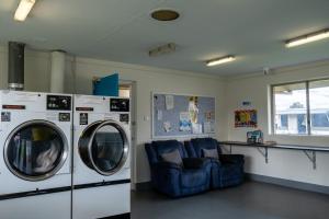 une chambre avec deux lave-linge et un canapé bleu dans l'établissement BIG4 Perth Midland Tourist Park, à Middle Swan