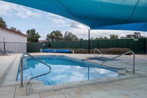 una piscina con una sombrilla azul en un patio en BIG4 Perth Midland Tourist Park, en Middle Swan