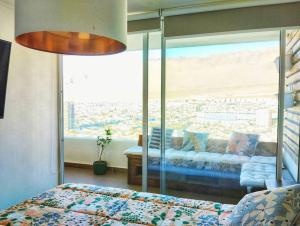 a bedroom with a bed and a large glass window at Departamento a pasos de PLAYA BRAVA! Cavancha in Iquique