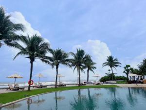 峴港的住宿－Luxury Beach Resort Apartments & Villas，棕榈树海滩旁的游泳池