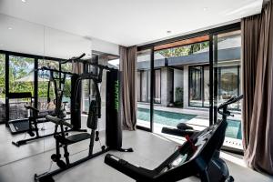 een fitnessruimte met 2 loopbanden en een zwembad bij Villa Livia by BaliSuperHost in Ubud