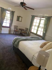 a bedroom with a large bed and two windows at Honeysuckle Cottages in Stanthorpe