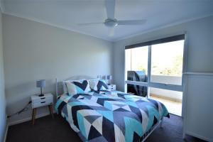 a bedroom with a blue and white bed and a window at Esplanade Sophistication Close To Town And Inlet Beach in Inverloch