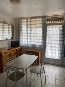 a kitchen with a table and chairs and windows at Gite aux grès des vents in Champeaux