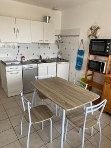 Il comprend une cuisine avec une table et des chaises en bois. dans l'établissement Gite aux grès des vents, à Champeaux