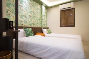 a bedroom with two beds and a window and a wall at FOODOTEL in Bangkok