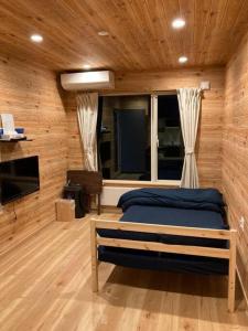 a bedroom with a bed in a room with wooden walls at はるの空 in Biei