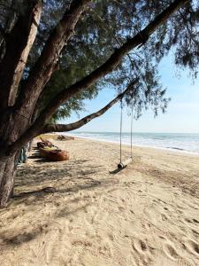 a swing hanging from a tree on the beach at Mumsa Beach Resort & Restaurant in Ban Huai Yang