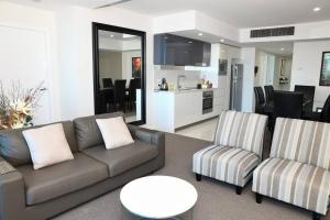 a living room with a couch and chairs and a kitchen at Spectacular 19th Floor Apartment in Heart of Surfers Paradise in Gold Coast