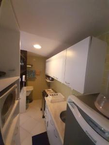 uma pequena cozinha com armários brancos e um lavatório em dúplex beira-mar em Maceió