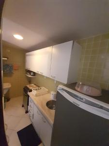 una pequeña cocina con armarios blancos y fregadero en dúplex beira-mar, en Maceió