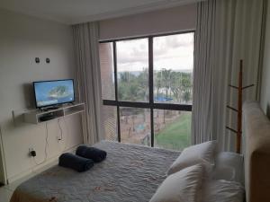 um quarto com uma cama, uma televisão e uma janela em dúplex beira-mar em Maceió