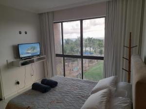 una camera da letto con un letto, una tv e una finestra di dúplex beira-mar a Maceió