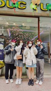 three girls wearing masks standing in front of a store at DT Hotel Hai Phong in Hai Phong