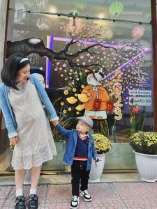 a woman and a child holding hands in front of a window at DT Hotel Hai Phong in Hai Phong