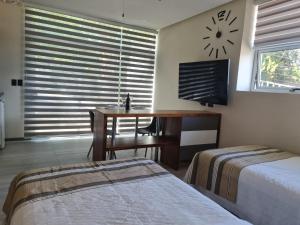 a bedroom with two beds and a desk and a clock on the wall at Cute Escazú Loft -Great view- in Escazu +19 photos
