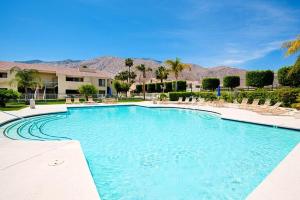 a large swimming pool with chairs and mountains in the background at Upscale 2Bed 2Bath Condo Prime Location WiFi Pools Kitchen Security in Palm Springs