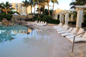 a pool with white lounge chairs in a resort at Stunning Apartment Best Ocean Views Surfers in Gold Coast