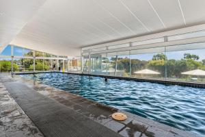 ein großer Pool in einem Gebäude mit Fenstern in der Unterkunft Bayvista at Silverwater in San Remo