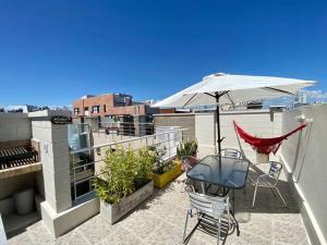 un patio con una mesa y una sombrilla en el techo en Departamento con terraza, parrilla y piscina en Buenos Aires