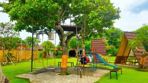 a playground in a park with a tree at Rich Farmer Eco House and Yoga in Pemuteran