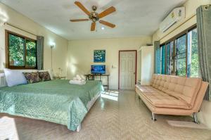 a bedroom with a bed and a couch and a ceiling fan at Tachang Garden Cottage in Ban Tha Chang