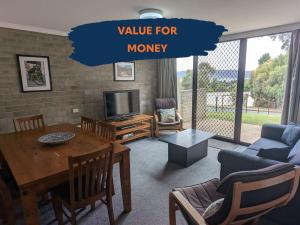 a living room with a table and a tv at Tanderra 4 in Jindabyne