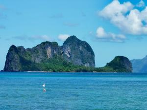 um pássaro na água com montanhas ao fundo em El Nido Beach Camp 