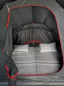 a bed in a black tent with two pillows at El Nido Beach Camp 