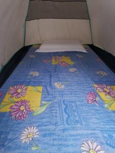 a bed with a blue blanket with flowers on it at El Nido Beach Camp 