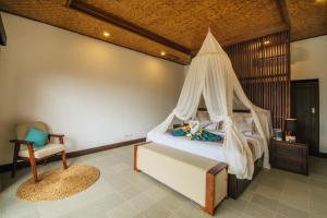 a bedroom with a canopy bed and a chair at Patal Kikian Villa in Sidemen