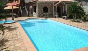 a large blue swimming pool in front of a house at Euro Vacances Guest House in Roches Brunes