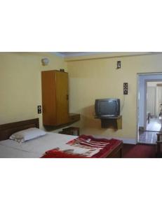 a bedroom with a bed and a tv in it at Alankar Lodge, Karagpur in Kharagpur