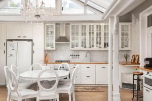 uma cozinha com armários brancos e uma mesa e cadeiras em The East-Redfern Mansion on Chelsea em Sidney