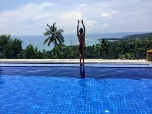 a woman standing on the edge of a swimming pool at Villa Umbrella Lombok in Senggigi 