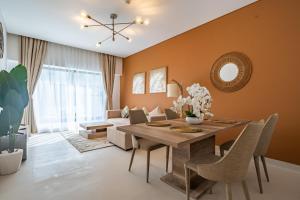 a dining room with orange walls and a wooden table and chairs at Primestay - 1BR in Prime Views in Al Meydan in Dubai