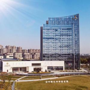 a large glass building in front of a city at Jingling Grand Hotel Gaochun in Gaochun