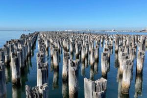 um grupo de postes de madeira na água em Amzing Ocean View Spacious Three Bedrooms Apartment Port Melbourne em Melbourne