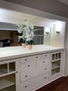 a white dresser with a mirror and flowers on it at 2 King Beds! Fantastic Stylish Bungalow home! in Fresno