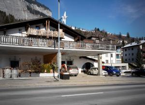 a building with a balcony with cars parked in a parking lot at Solution-Grischun, Parkplatz - Küche- Wäschetrokner- Kaffee, Tee in Flims