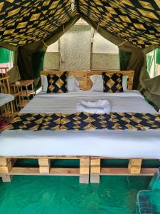 two beds in a tent with a pool of water at Pacha Waterfront Nithi in Chuka